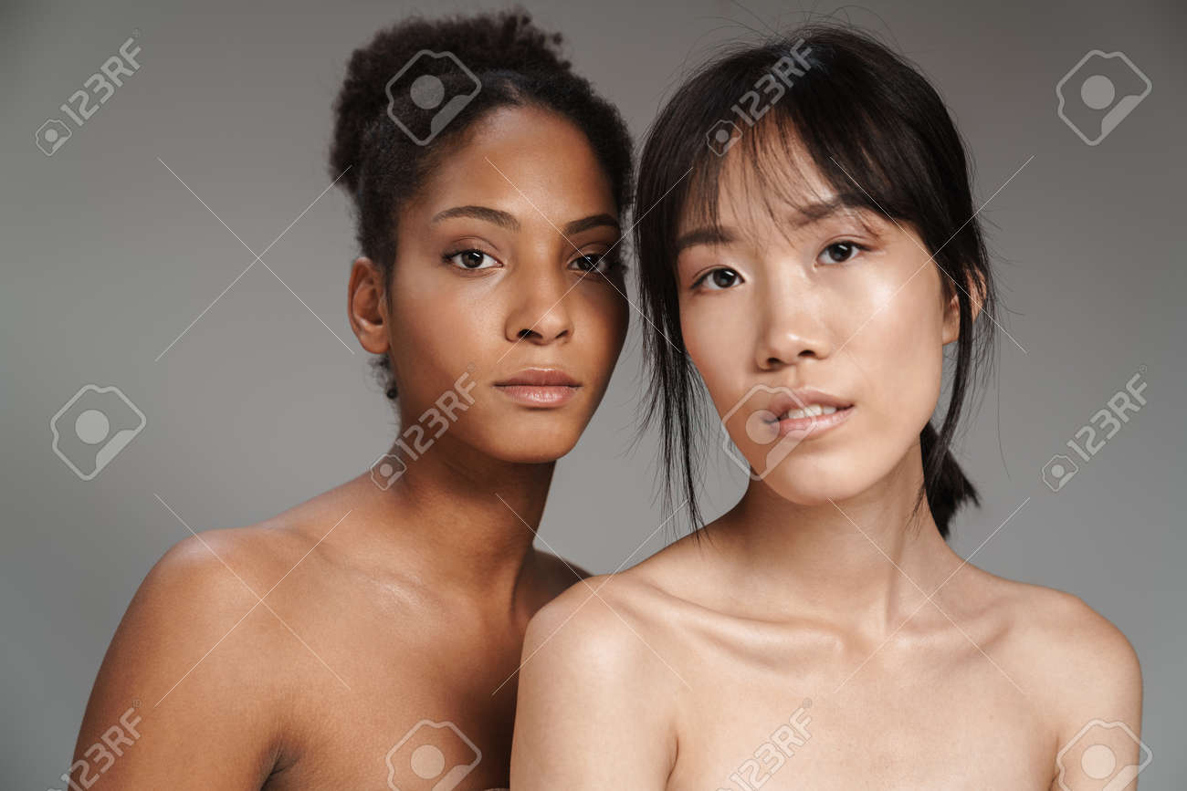 Portrait Of Two Multinational Half-naked Women Posing Together And Looking  At Camera Isolated Over Grey Background Stock Photo, Picture and Royalty  Free Image. Image 145416466.