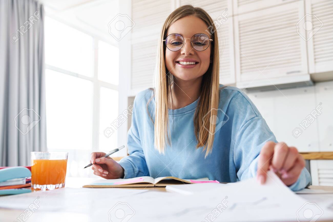 Image Of Pleased Charming Woman In Eyeglasses Smiling While Studying With Exercise Books At Home Stock Photo Picture And Royalty Free Image Image 147844332