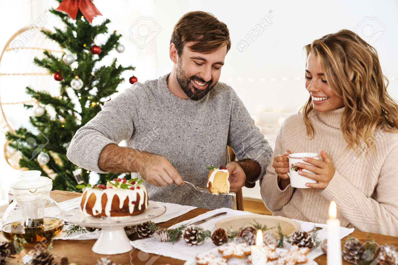 Charming cheerful couple eating pie while having Christmas dinner in cozy room - 165073246 Charming cheerful couple eating pie while having Christmas dinner in cozy room - 165073246