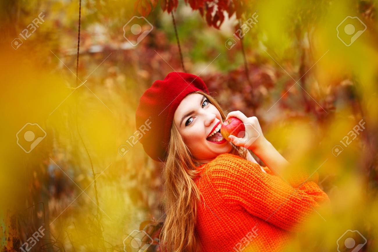 Pretty girl in a beret and a sweater in autumn park, holding a ripe apple and smiling. The girl bites ripe apple. The girl white smile. The concept of healthy teeth. - 47880331 Pretty girl in a beret and a sweater in autumn park, holding a ripe apple and smiling. The girl bites ripe apple. The girl white smile. The concept of healthy teeth. - 47880331