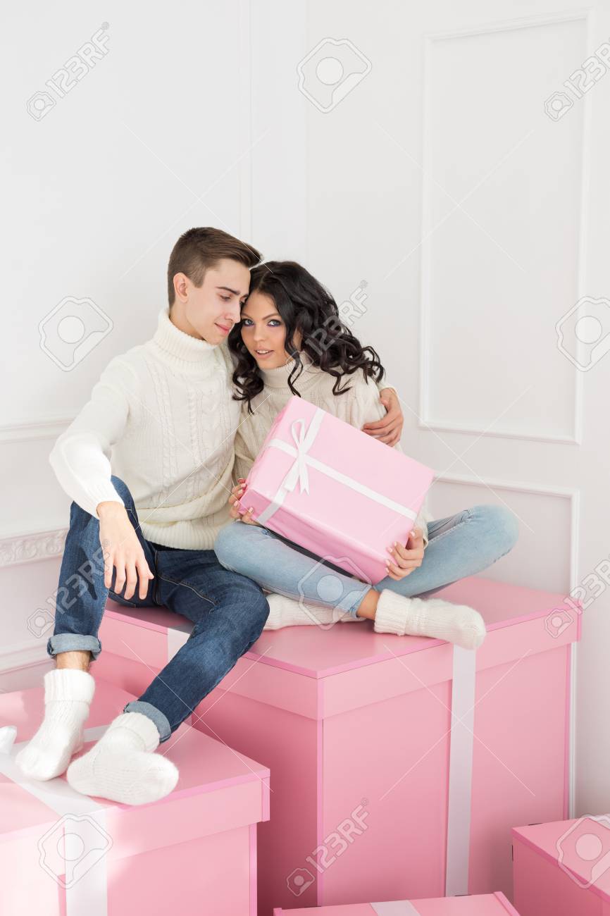 Regali Di Natale Per Giovani Coppie.Immagini Stock Una Coppia Di Giovani Innamorati E Seduta Sui Regali Uomo Che Abbraccia La Ragazza Ha In Mano Un Regalo Rosa Vacanze Felice Anno Nuovo Buon Natale San Valentino Compleanno