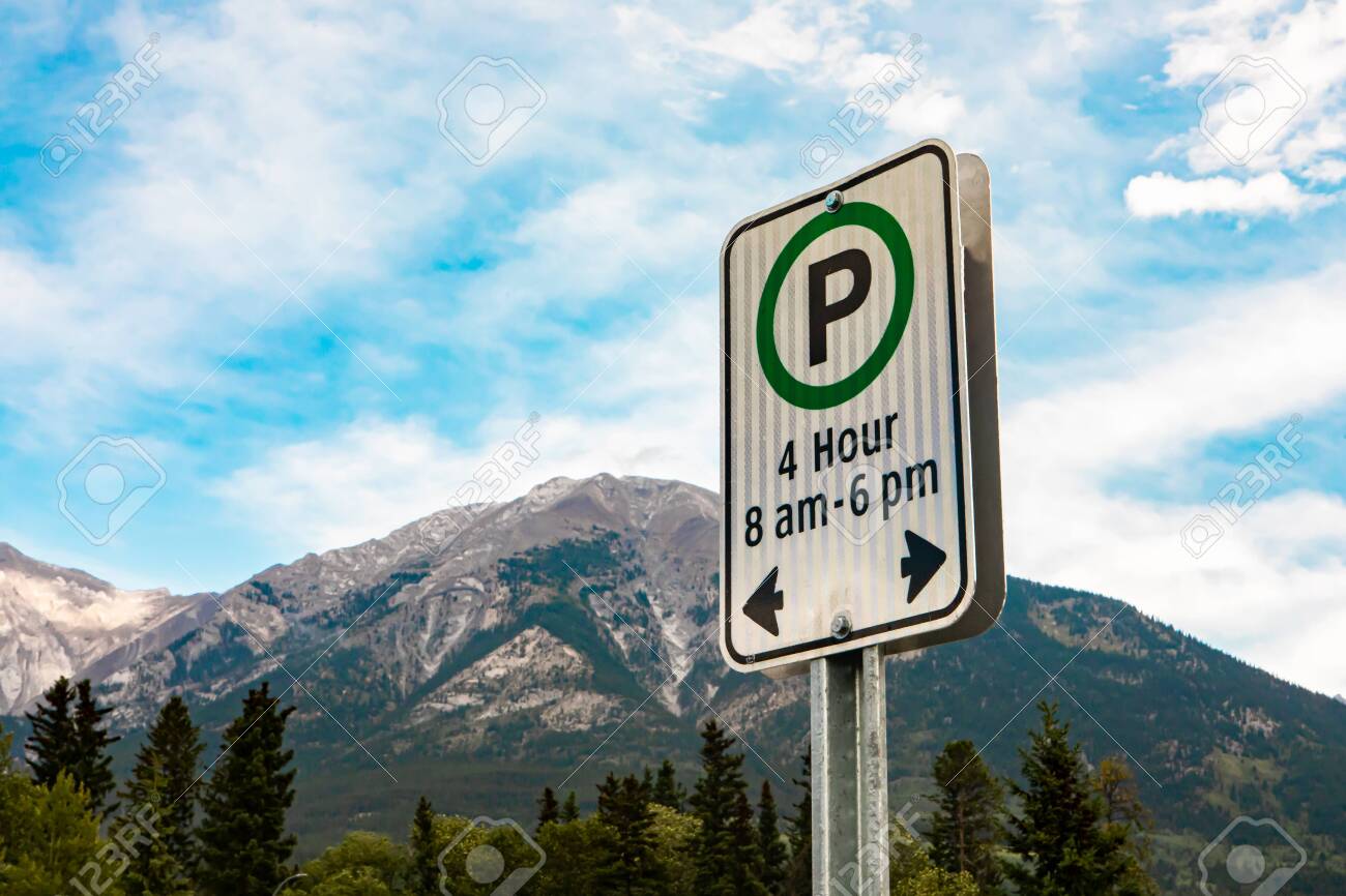 white sign with a green circle, 4 hours parking on specific times 8 am - 6 pm sign, against mountains and the blue sky, British Columbia, Canada - 136810407 white sign with a green circle, 4 hours parking on specific times 8 am - 6 pm sign, against mountains and the blue sky, British Columbia, Canada - 136810407