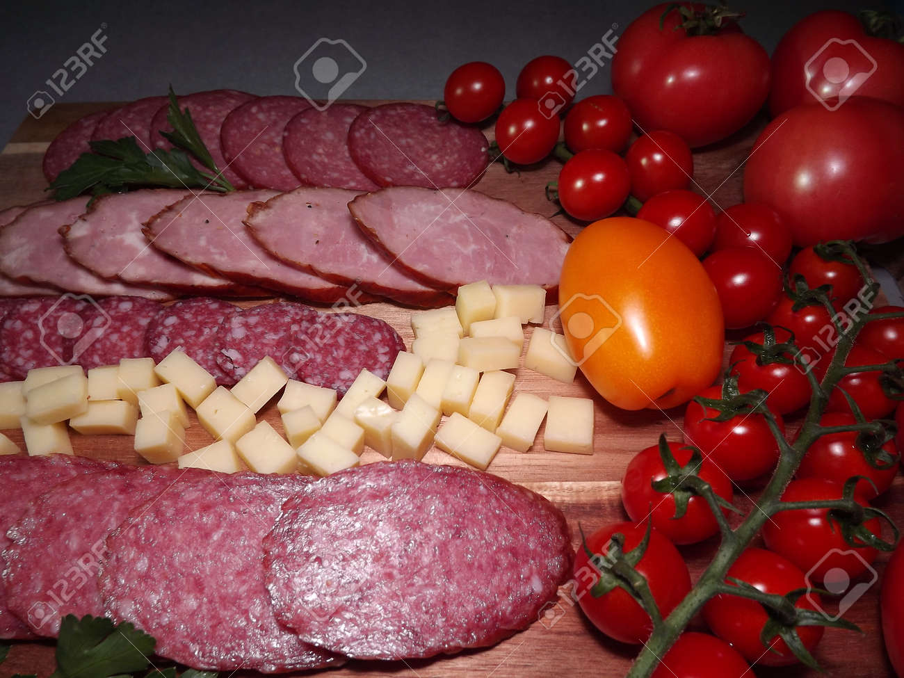 slicing smoked sausage of four varieties with cheese and red and yellow tomatoes and cherry tomatoes. High quality photo - 166249300 slicing smoked sausage of four varieties with cheese and red and yellow tomatoes and cherry tomatoes. High quality photo - 166249300