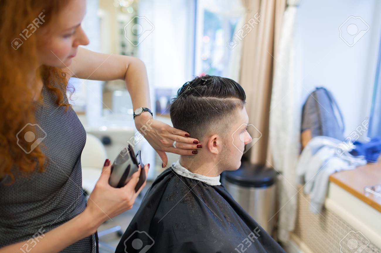 Girl Hairdresser With Curly Red Hair Cuts Young Handsome Guy