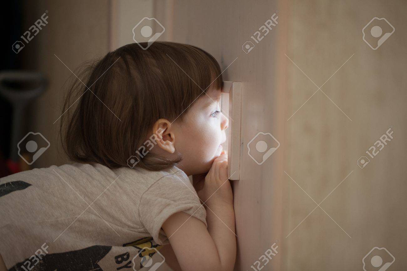 Le Petit Garçon Regarde Dans La Fenêtre De La Porte. Un Enfant Espionner  Ses Parents Derrière La Porte De La Chambre Fermée Banque D'images Et  Photos Libres De Droits. Image 86251674.