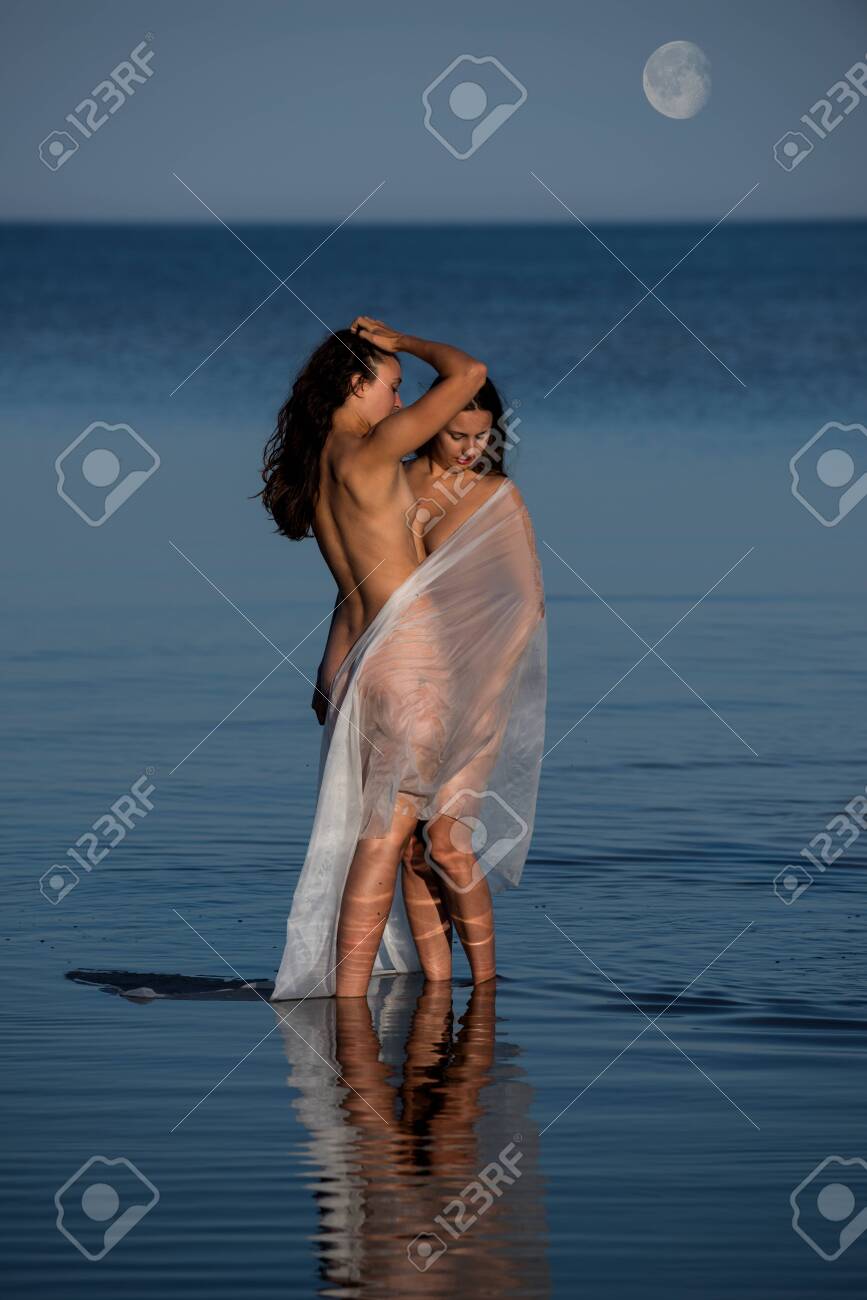 Two young with white shawl posing on the beach in the evening. Sexy brunettes enjoying summer time outdoors - 133376946 Two young with white shawl posing on the beach in the evening. Sexy brunettes enjoying summer time outdoors - 133376946