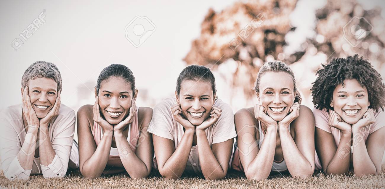 Portrait of smiling women lying in a row for cancer awarness in park - 85858207 Portrait of smiling women lying in a row for cancer awarness in park - 85858207