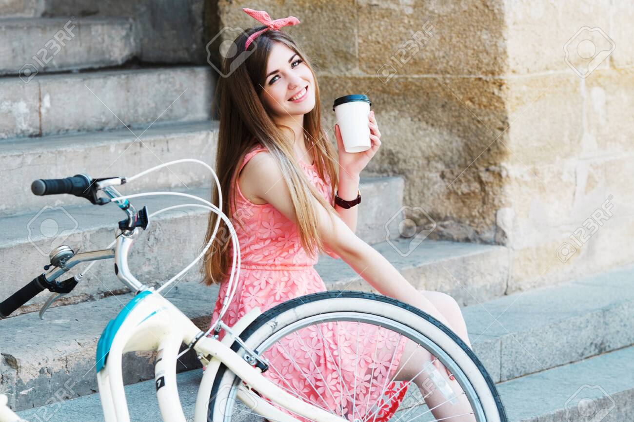girl smiling with a cup of coffee and vintage bicycle - 122488772 girl smiling with a cup of coffee and vintage bicycle - 122488772