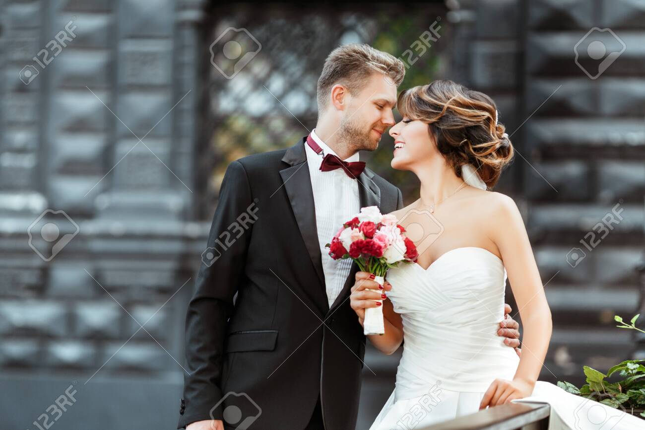 Bride and bridegroom standing with bouquet and smiling - 122381118 Bride and bridegroom standing with bouquet and smiling - 122381118