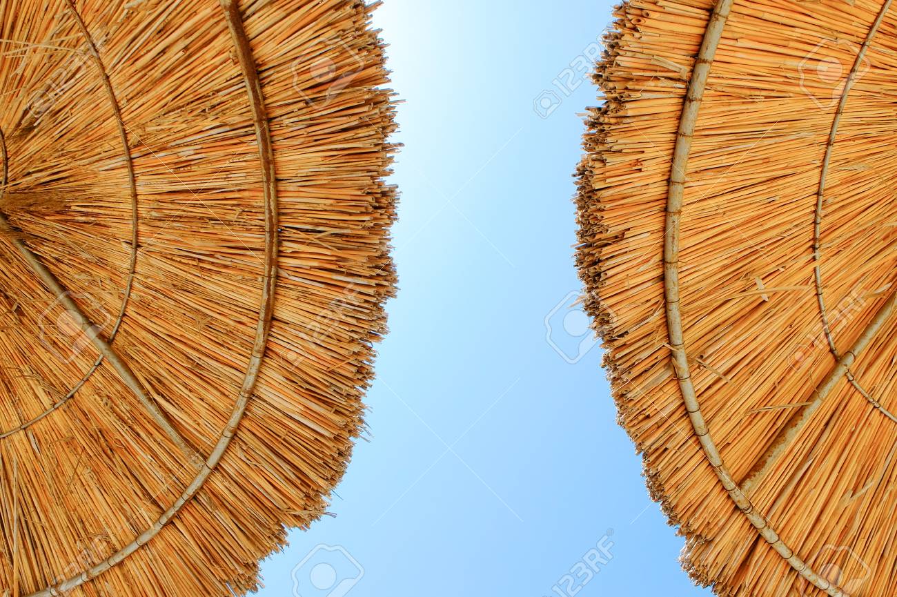 Beach umbrellas made of straw at blue sky background - 122493985 Beach umbrellas made of straw at blue sky background - 122493985