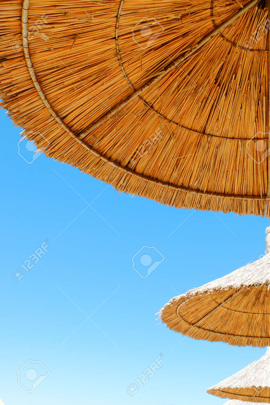 Beach umbrellas made of straw at blue sky background - 122493988 Beach umbrellas made of straw at blue sky background - 122493988