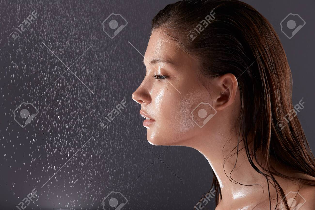 pretty brunette face in profile with water drops on grey background, copy space, wet woman body, moisturizing girl close-up - 123711111 pretty brunette face in profile with water drops on grey background, copy space, wet woman body, moisturizing girl close-up - 123711111