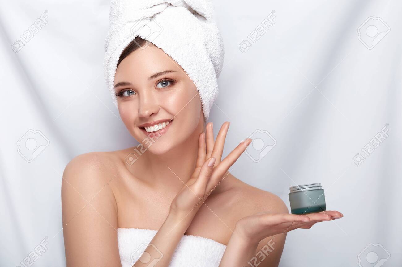 beautiful girl in bath towel on her head holding cream and touching her face on white,facial treatment with perfect skin lady - 123711195 beautiful girl in bath towel on her head holding cream and touching her face on white,facial treatment with perfect skin lady - 123711195