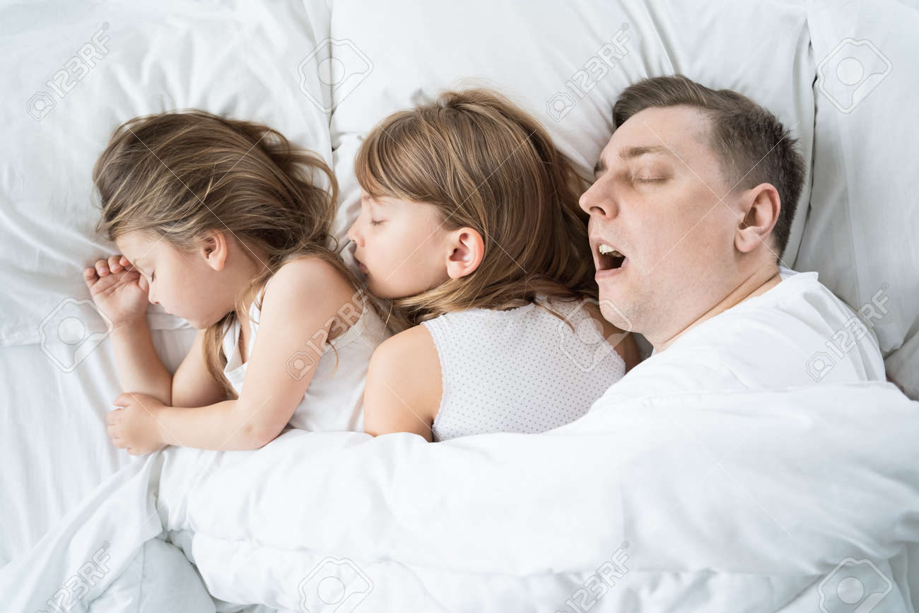 Kids, daughters, dad sleep together in bed on pillows under blanket. Father is snoring hard. Family joint sleeping. Insomnia, night bedtime. Sweet dreams. arly wake up, rise to kindergarten, school, work. - 157678009 Kids, daughters, dad sleep together in bed on pillows under blanket. Father is snoring hard. Family joint sleeping. Insomnia, night bedtime. Sweet dreams. arly wake up, rise to kindergarten, school, work. - 157678009