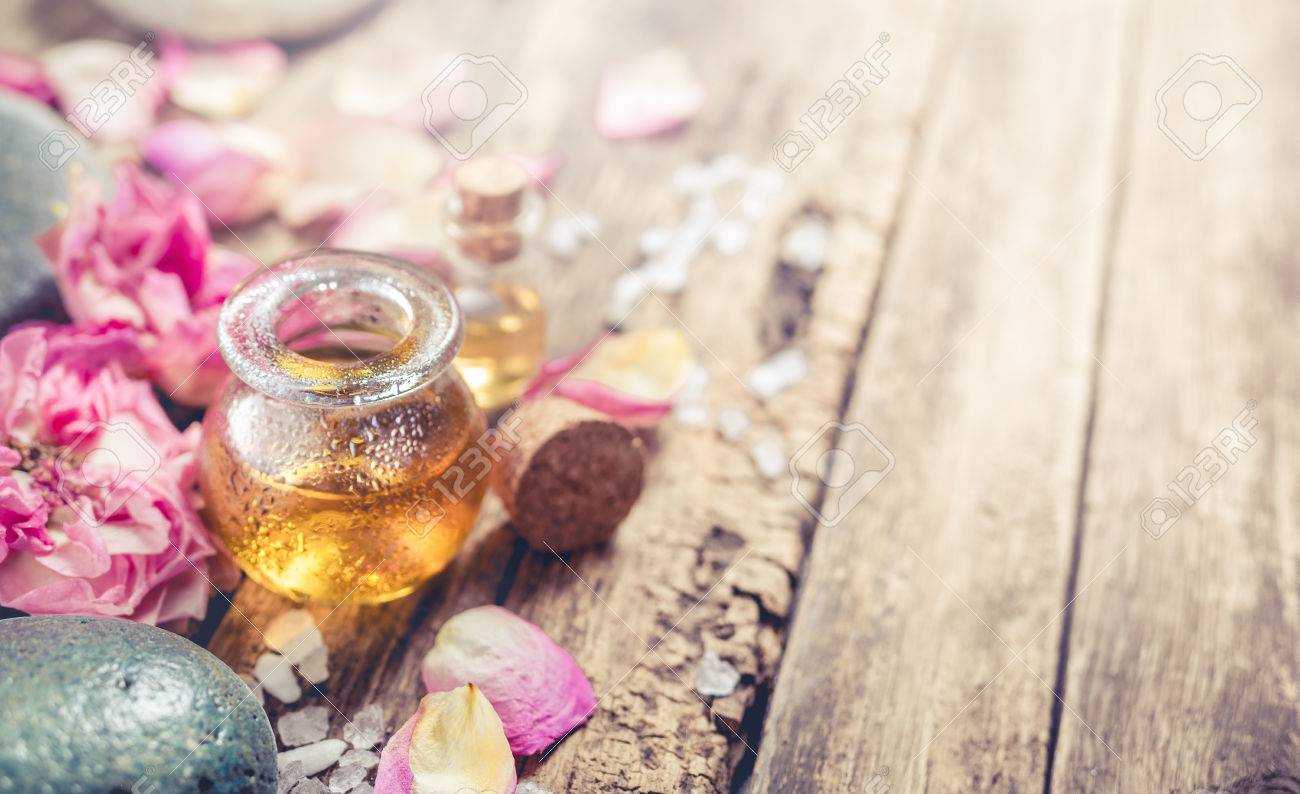 Massage Oil Petals Flowers And Zen Stones SPA Background In A Rustic Style With Massage Oil Petals Flowers And Zen Stones SPA Background In A Rustic Style With