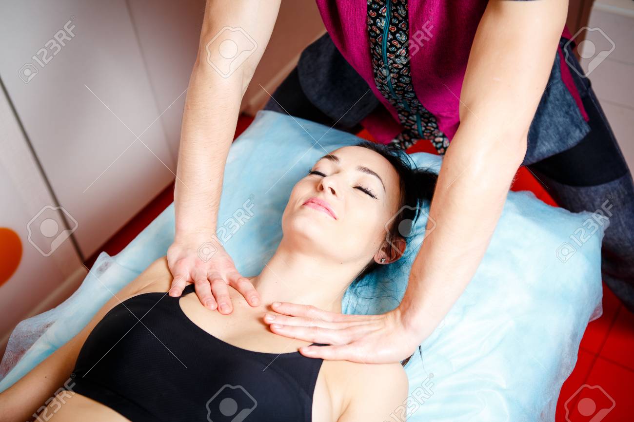 美しい体を得るための美容スタジオのマッサージテーブルに横たわっている女の子のオーブンでリラックスした古典的なマッサージを行う若いハンサムな男性マッサージセラピスト の写真素材 画像素材 Image