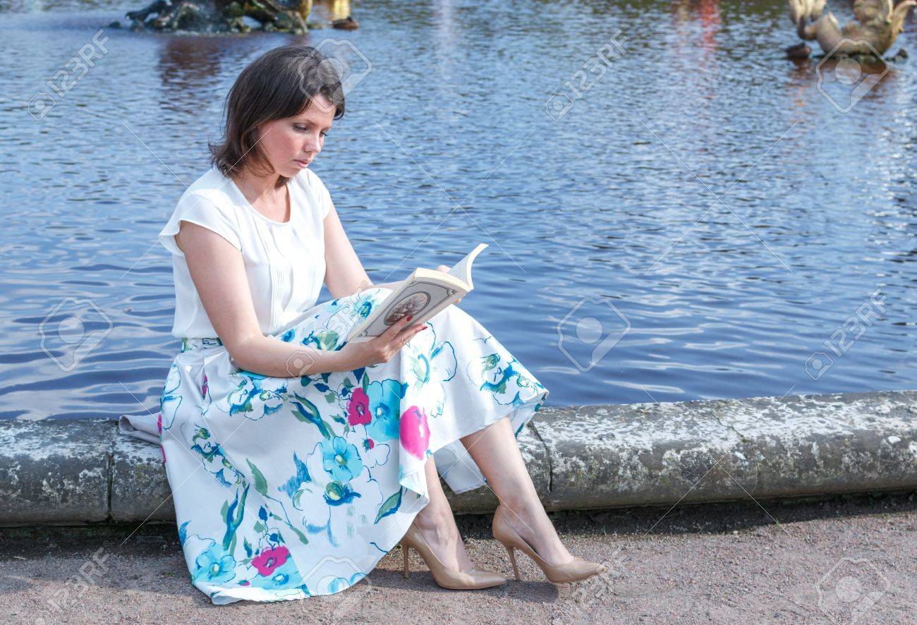 素敵なかなり若い流行に敏感な女性のファッションはブラウスとロング スカートの緑の草の上に座っています の写真素材 画像素材 Image