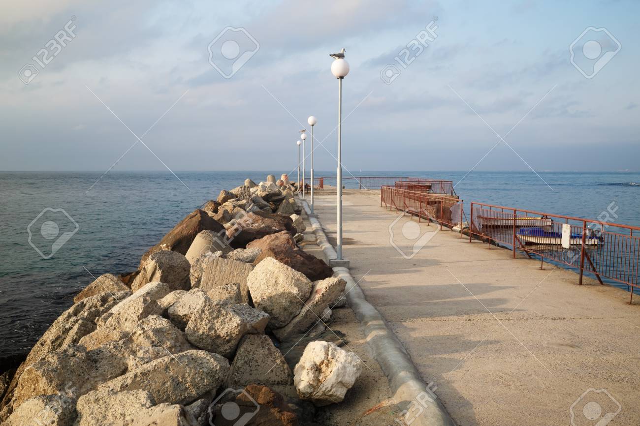 海に伸びる防波堤。街灯が穴を開けます。黒海の海岸に穏やかな夏の日 