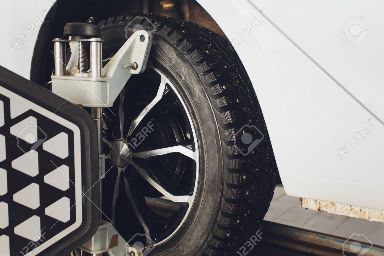 A Car on the Car Steering Wheel Balancer and Calibrate with laser reflector attach on each tire to center driving adjust in the garage - 117845471 A Car on the Car Steering Wheel Balancer and Calibrate with laser reflector attach on each tire to center driving adjust in the garage - 117845471