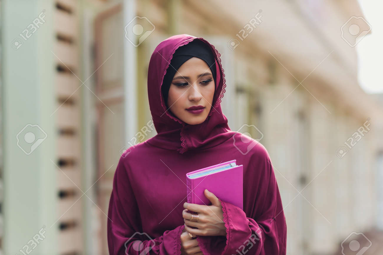 Confident Arab businessman smiling and walks of Dubai. Arab Business vumen hijab is in the streets against the skyscrapers of Dubai. The woman is dressed in a black abaya. - 169483460 Confident Arab businessman smiling and walks of Dubai. Arab Business vumen hijab is in the streets against the skyscrapers of Dubai. The woman is dressed in a black abaya. - 169483460
