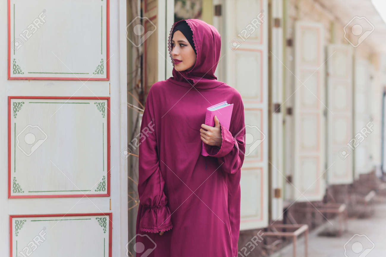 Confident Arab businessman smiling and walks of Dubai. Arab Business vumen hijab is in the streets against the skyscrapers of Dubai. The woman is dressed in a black abaya. - 169483463 Confident Arab businessman smiling and walks of Dubai. Arab Business vumen hijab is in the streets against the skyscrapers of Dubai. The woman is dressed in a black abaya. - 169483463