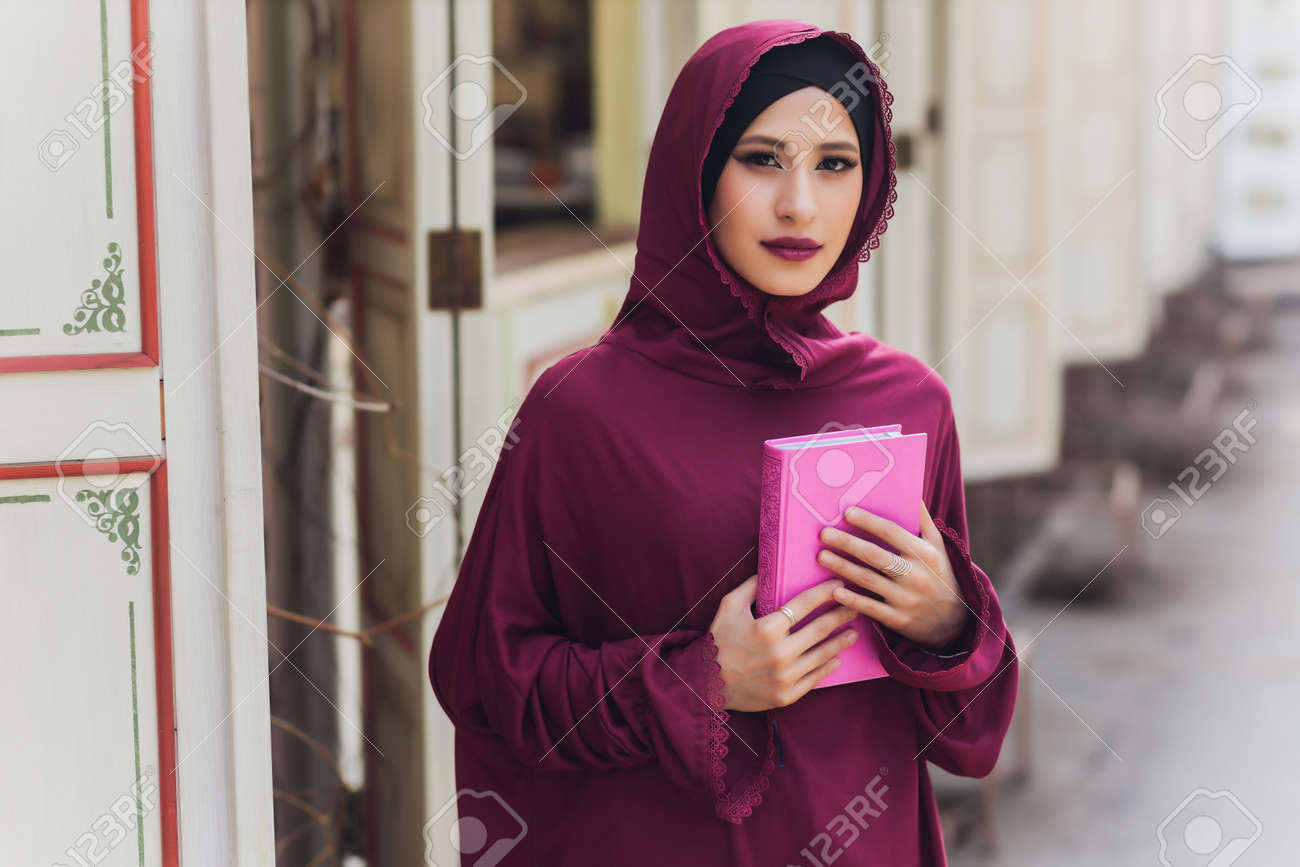 Confident Arab businessman smiling and walks of Dubai. Arab Business vumen hijab is in the streets against the skyscrapers of Dubai. The woman is dressed in a black abaya. - 169483466 Confident Arab businessman smiling and walks of Dubai. Arab Business vumen hijab is in the streets against the skyscrapers of Dubai. The woman is dressed in a black abaya. - 169483466