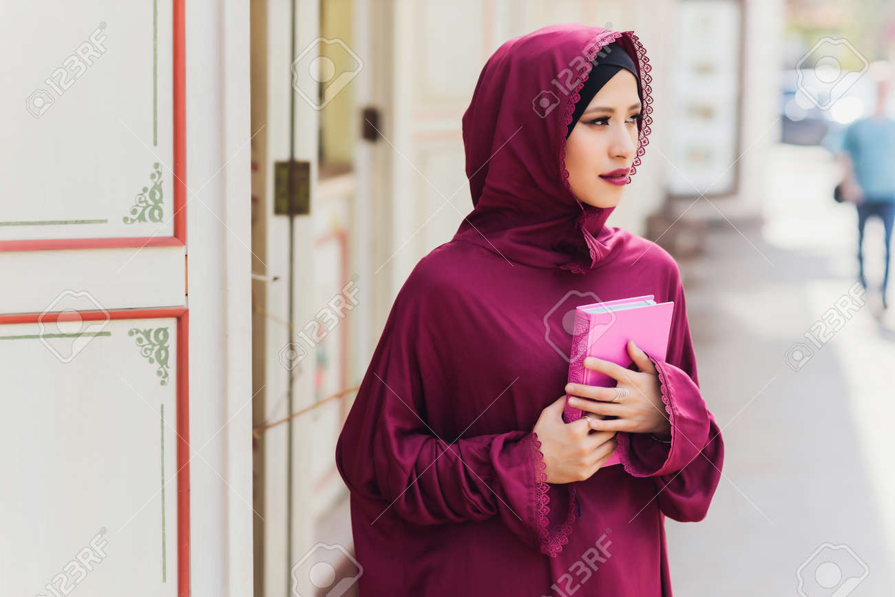 Confident Arab businessman smiling and walks of Dubai. Arab Business vumen hijab is in the streets against the skyscrapers of Dubai. The woman is dressed in a black abaya. - 169483467 Confident Arab businessman smiling and walks of Dubai. Arab Business vumen hijab is in the streets against the skyscrapers of Dubai. The woman is dressed in a black abaya. - 169483467