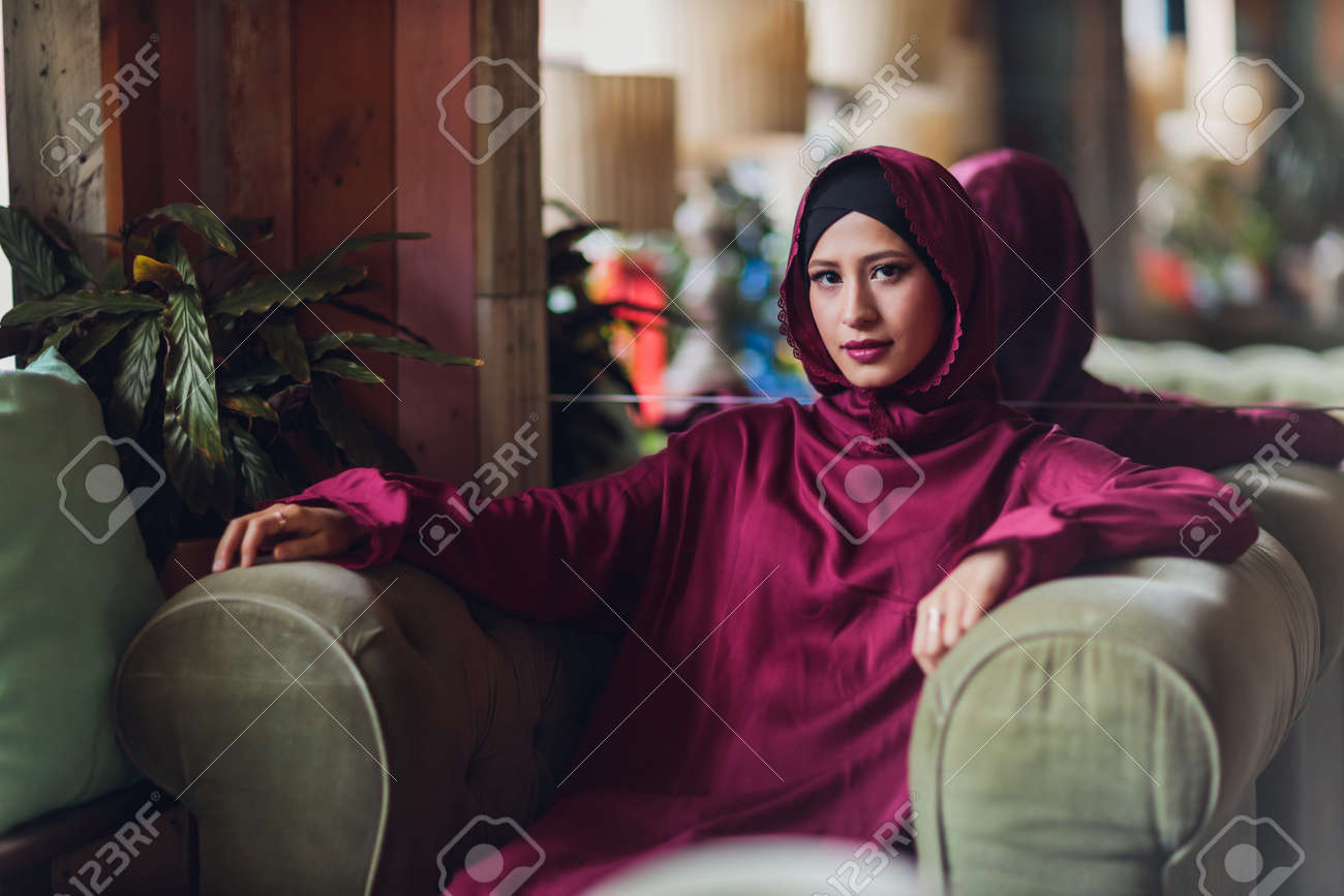 Arabian young muslim woman sitting in a cafe. - 169483501 Arabian young muslim woman sitting in a cafe. - 169483501