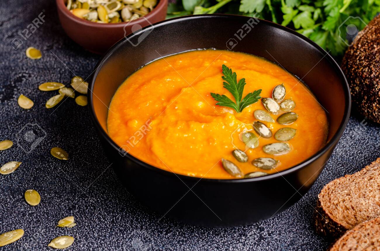 Traditional Ukrainian autumn cream soup of pumpkins and carrots with seeds and parsley on a dark background. Healthy eating concept. Horizontal orientation. Close-up. - 142276927 Traditional Ukrainian autumn cream soup of pumpkins and carrots with seeds and parsley on a dark background. Healthy eating concept. Horizontal orientation. Close-up. - 142276927