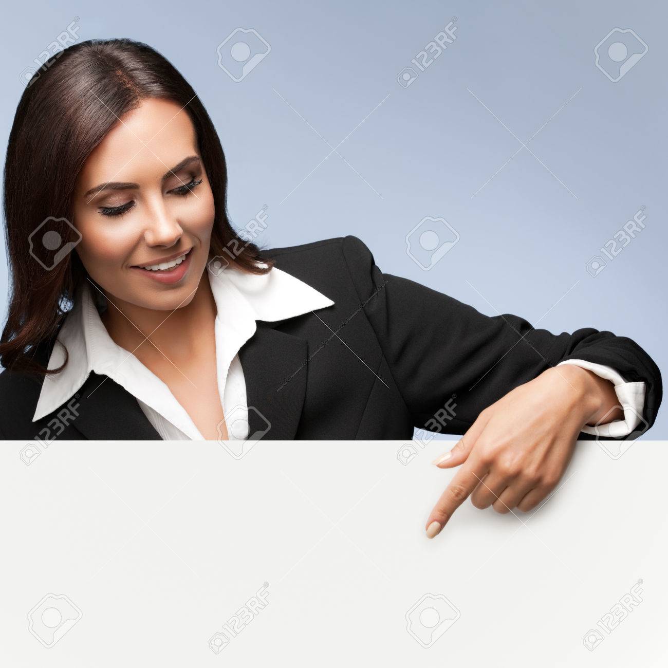 Portrait of happy smiling young businesswoman in black suit, showing blank signboard with blank copyspace area for slogan or text, over grey background - 51350129 Portrait of happy smiling young businesswoman in black suit, showing blank signboard with blank copyspace area for slogan or text, over grey background - 51350129