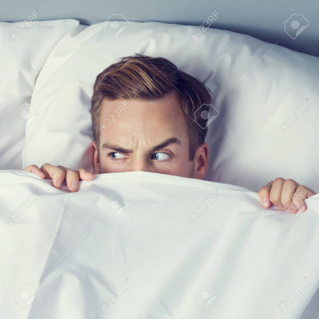Young Man Peeping From Bedsheet On The Bed At Bedroom Caucasian