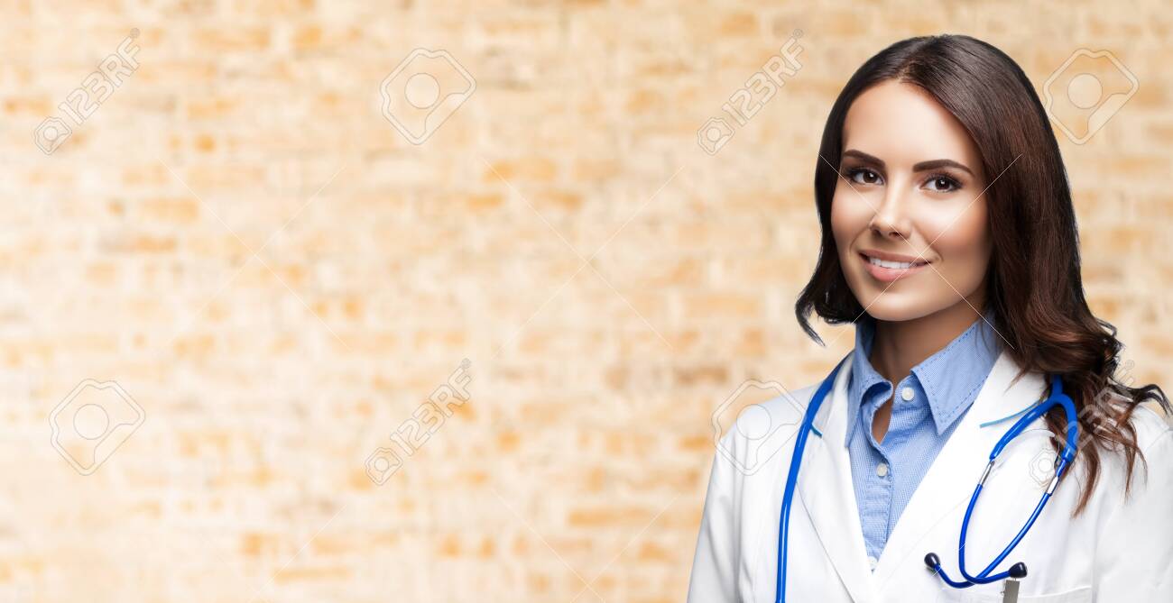 Portrait picture of happy smiling female doctor in white uniform coat and stethoscope, over loft style wall background. Healthcare, medical, medicine specialist - concept. Copy space. - 146299334 Portrait picture of happy smiling female doctor in white uniform coat and stethoscope, over loft style wall background. Healthcare, medical, medicine specialist - concept. Copy space. - 146299334