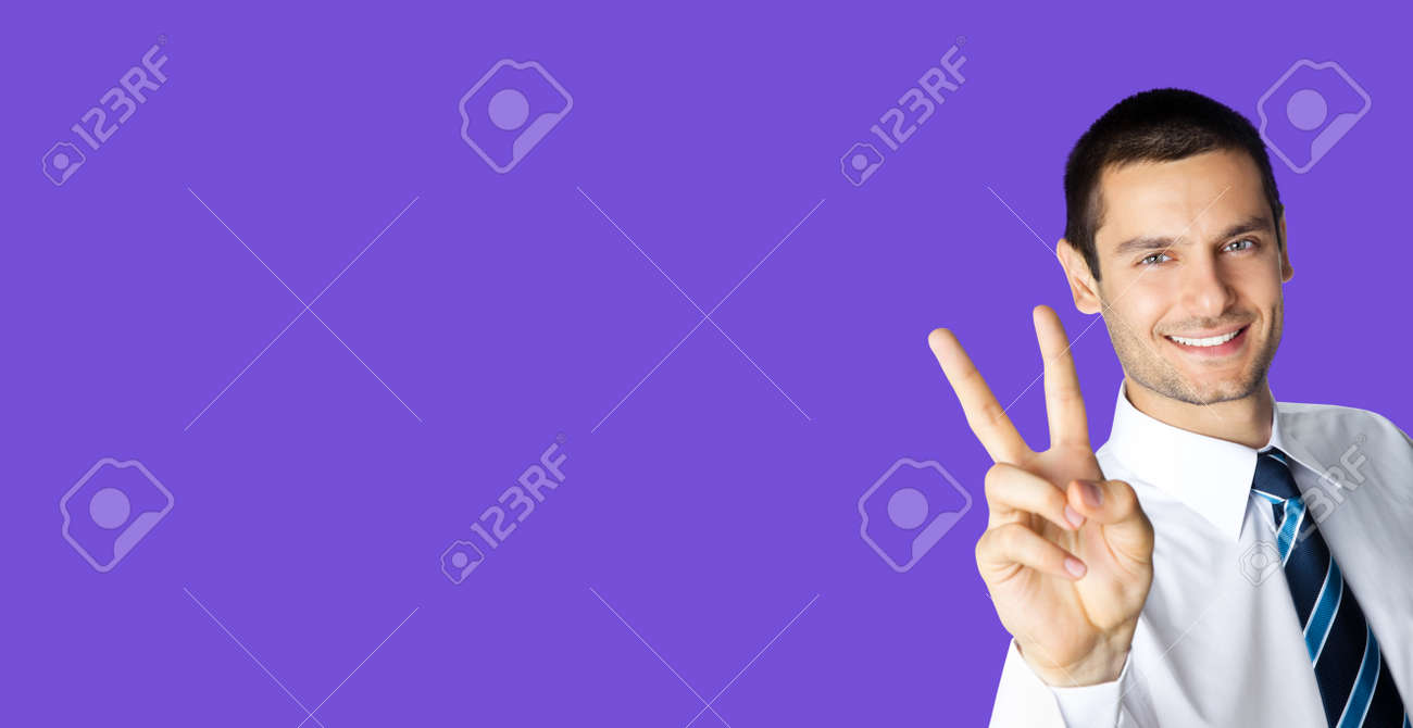 Businessman in white confident shirt and tie showing two fingers or victory gesture, over violet purple color background. Happy smiling gesturing brunette man at studio. Business ad concept. - 171559974 Businessman in white confident shirt and tie showing two fingers or victory gesture, over violet purple color background. Happy smiling gesturing brunette man at studio. Business ad concept. - 171559974