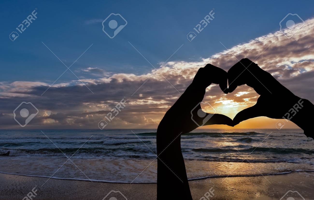 日の出の海によってハートの形をした手のシルエット の写真素材 画像素材 Image