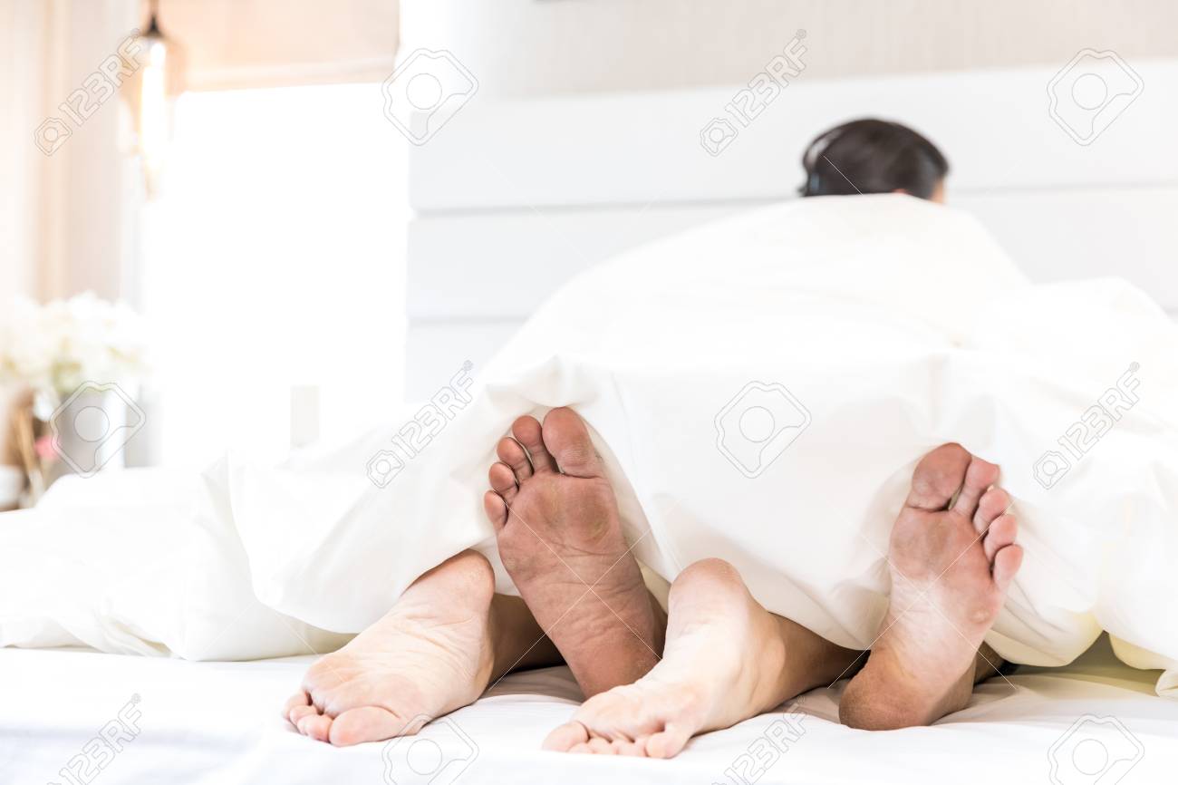 Couple legs tangled under sheets post-passion sensual erotica aftermath