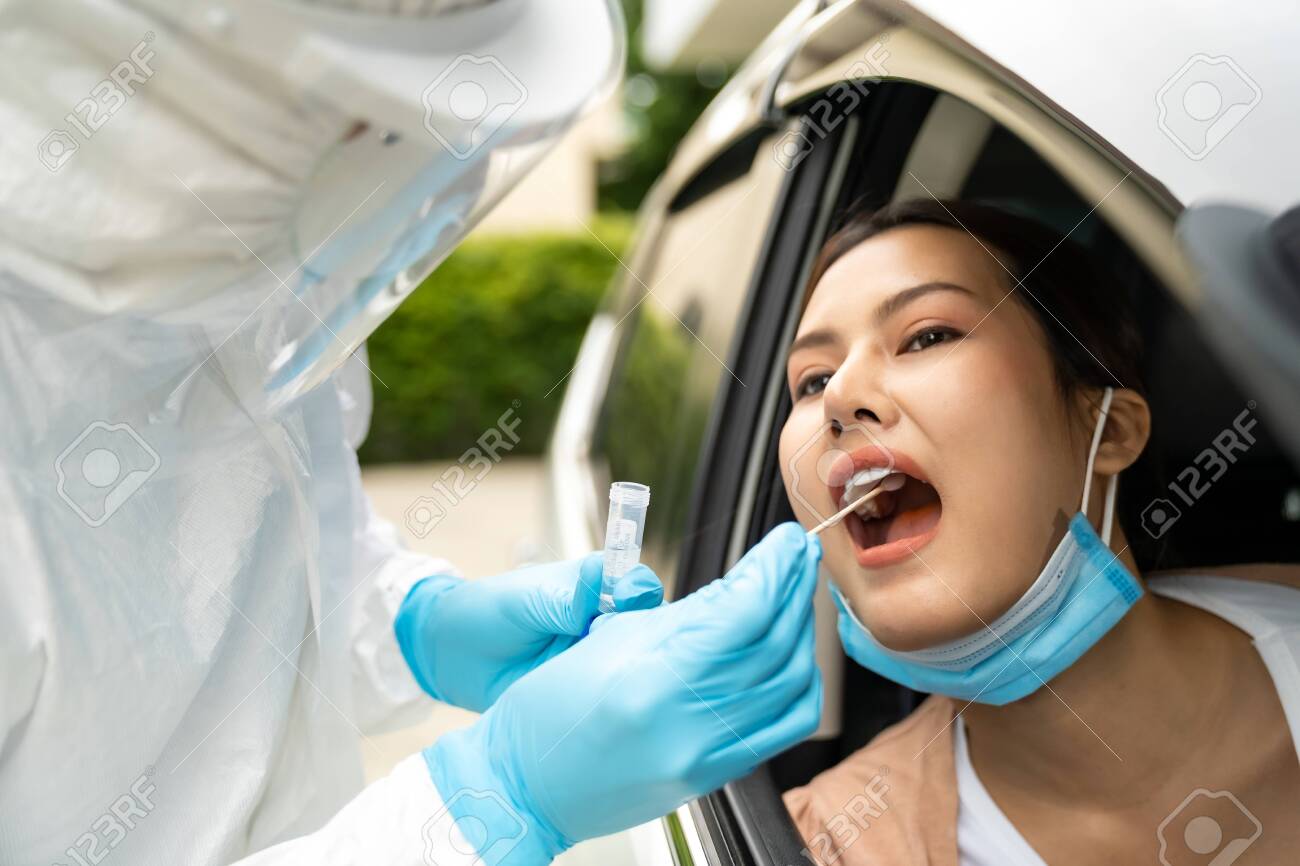 Portrait of asian woman drive thru coronavirus covid-19 test by medical staff with PPE suit by throat swab. New normal healthcare drive thru service and medical concept. - 151463220 Portrait of asian woman drive thru coronavirus covid-19 test by medical staff with PPE suit by throat swab. New normal healthcare drive thru service and medical concept. - 151463220