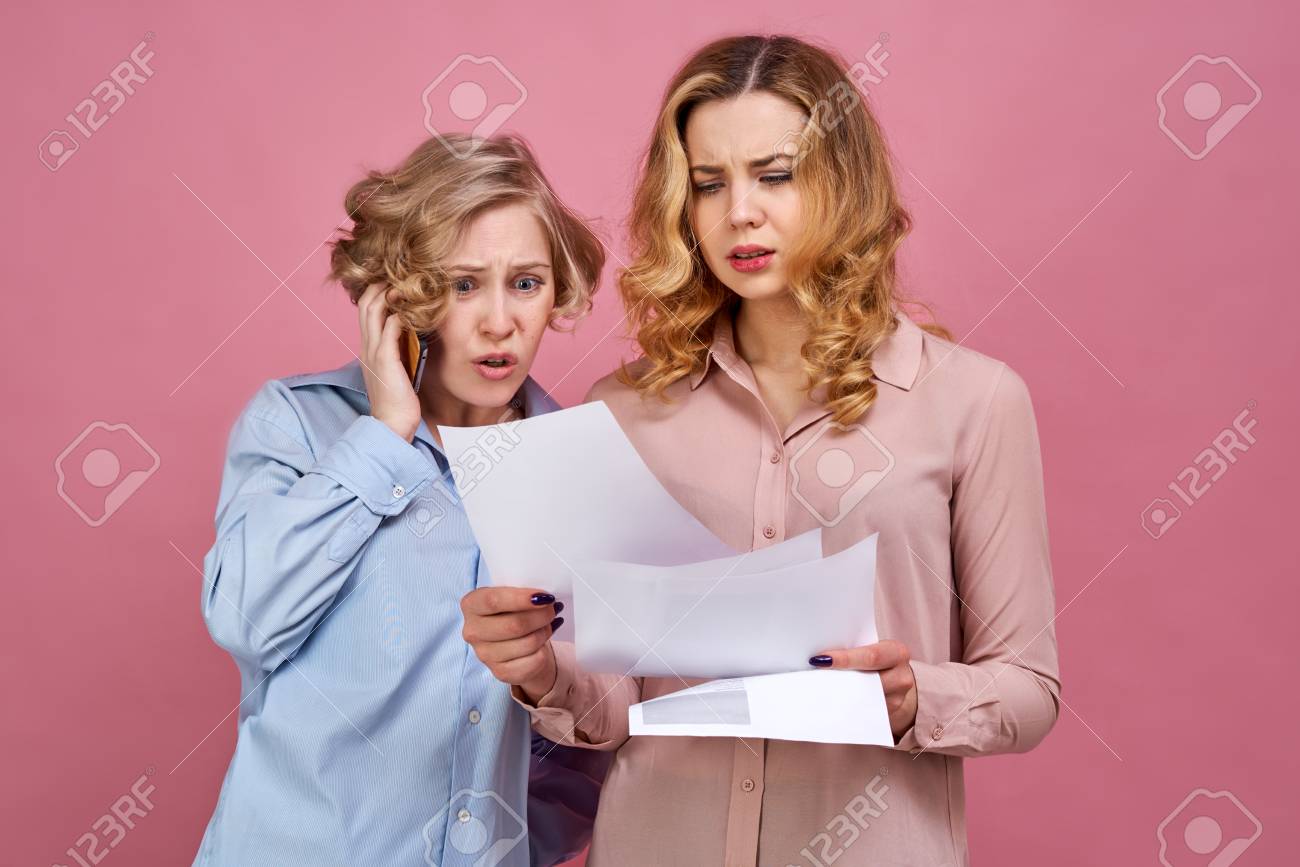 Two Young Girls Pose For Studio Portrait On Isolated Background Negative Emotions On Face Are Caused Two Young Girls Pose For Studio Portrait On Isolated Background Negative Emotions On Face Are Caused