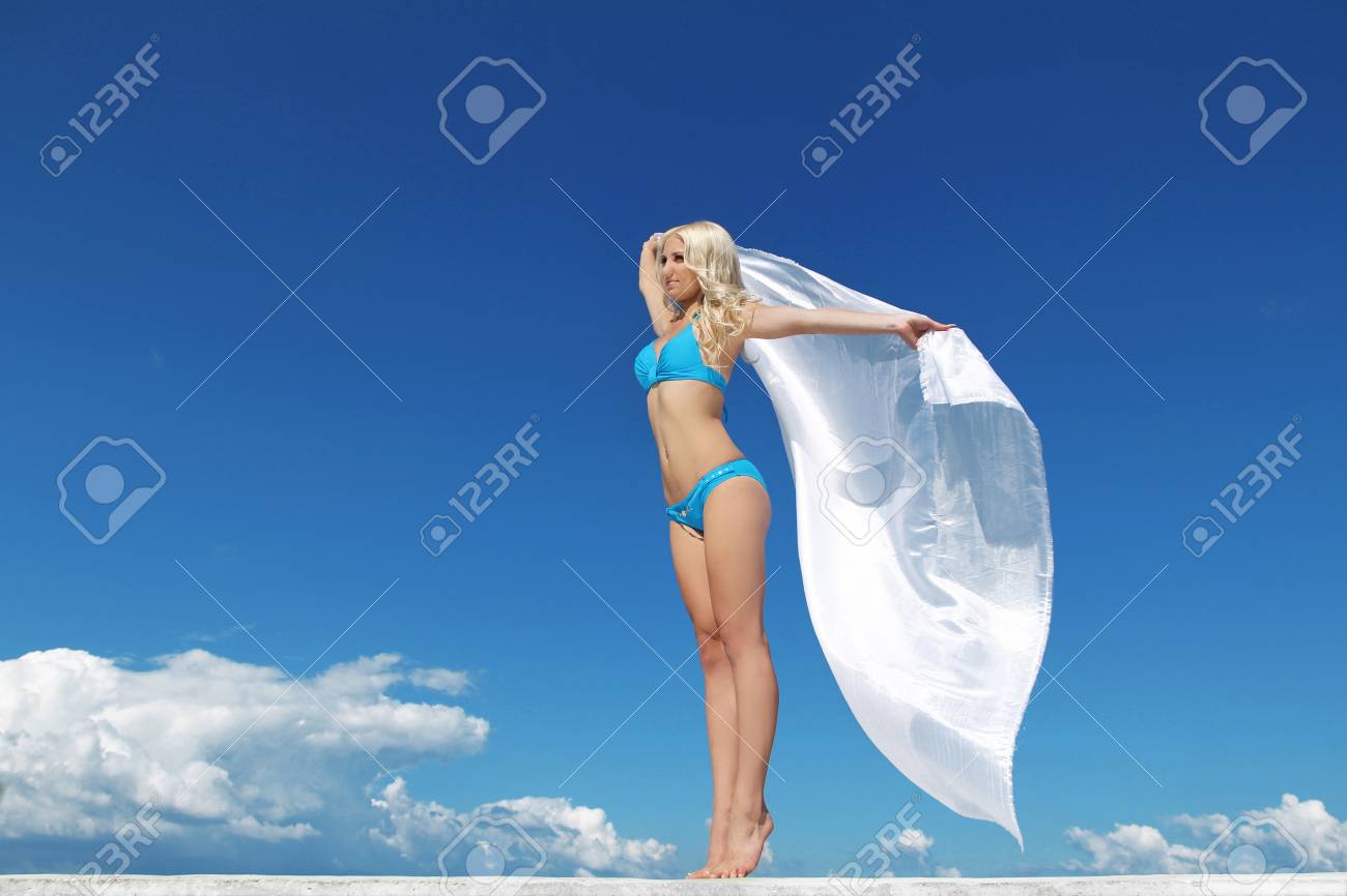 青い空の下の白い布の大きな部分を持つ美しい少女の屋外のポートレート の写真素材 画像素材 Image