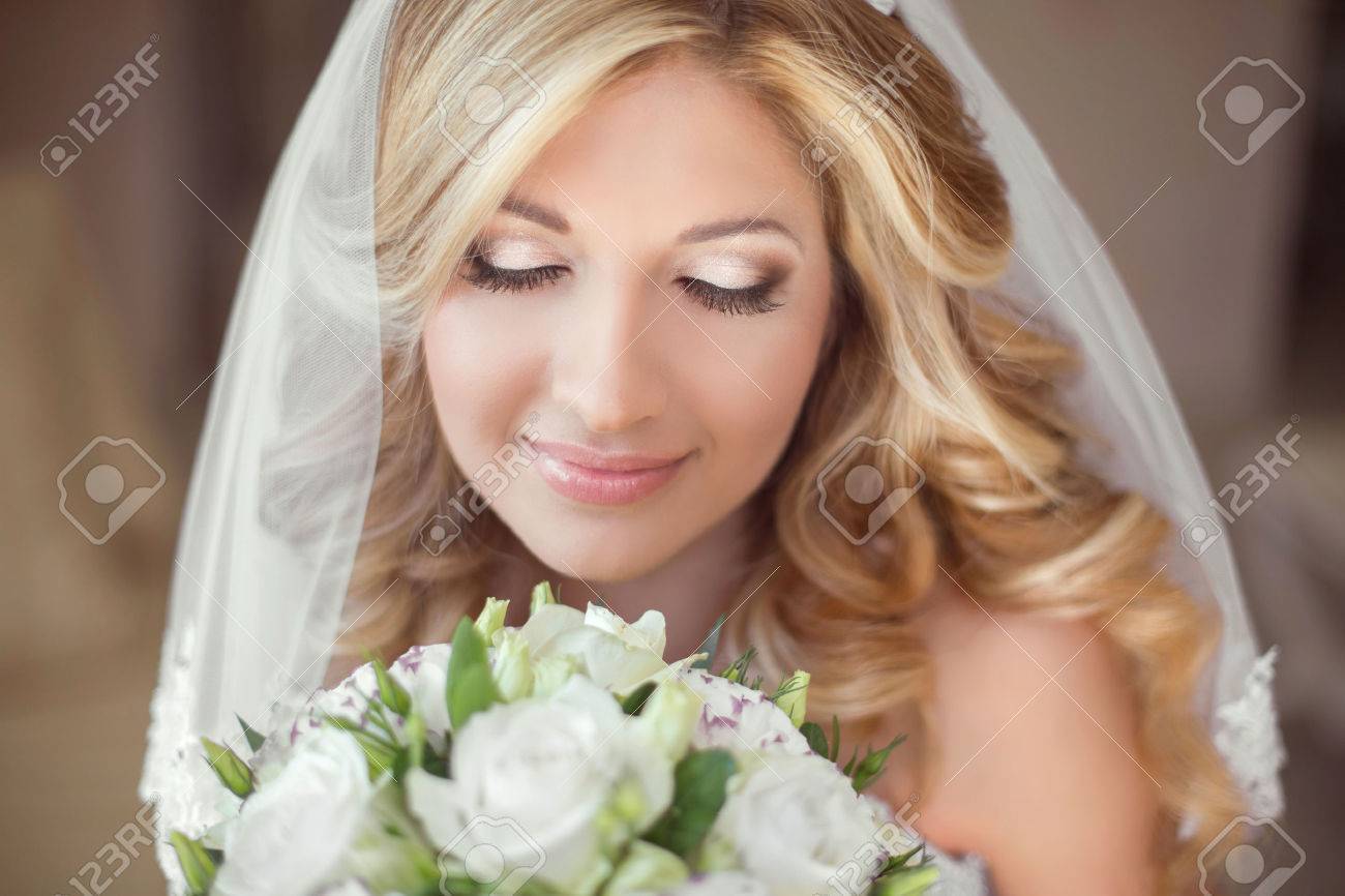 花の結婚式の花束に美しい花嫁 メイク 金髪巻き毛のヘアスタイル 笑顔の若い女性 の写真素材 画像素材 Image