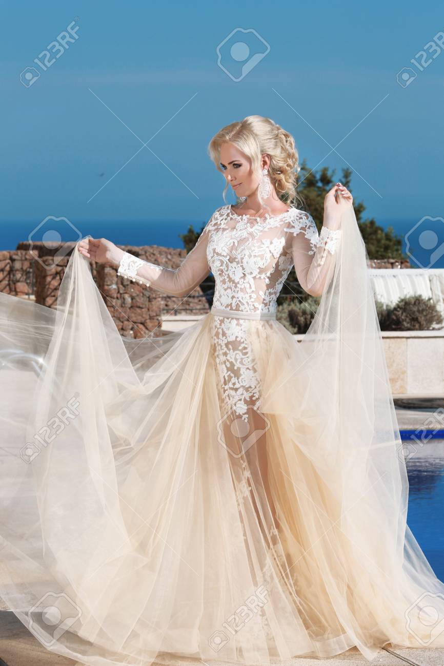Happy blond bride in fashion wedding dress with blowing beige..