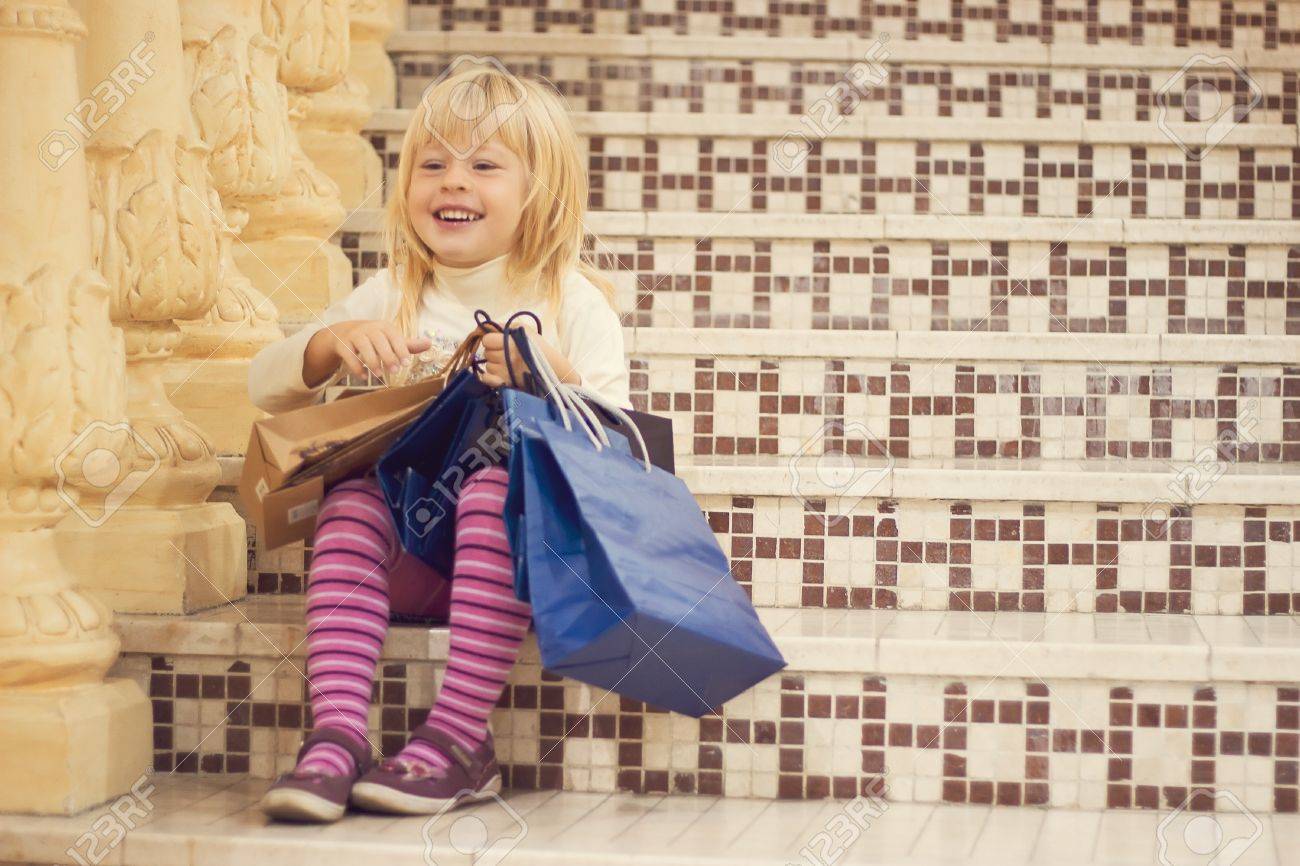 満足しているブロンドの女の子 3 歳明るい服を着て買い物と階段の上に座って の写真素材 画像素材 Image