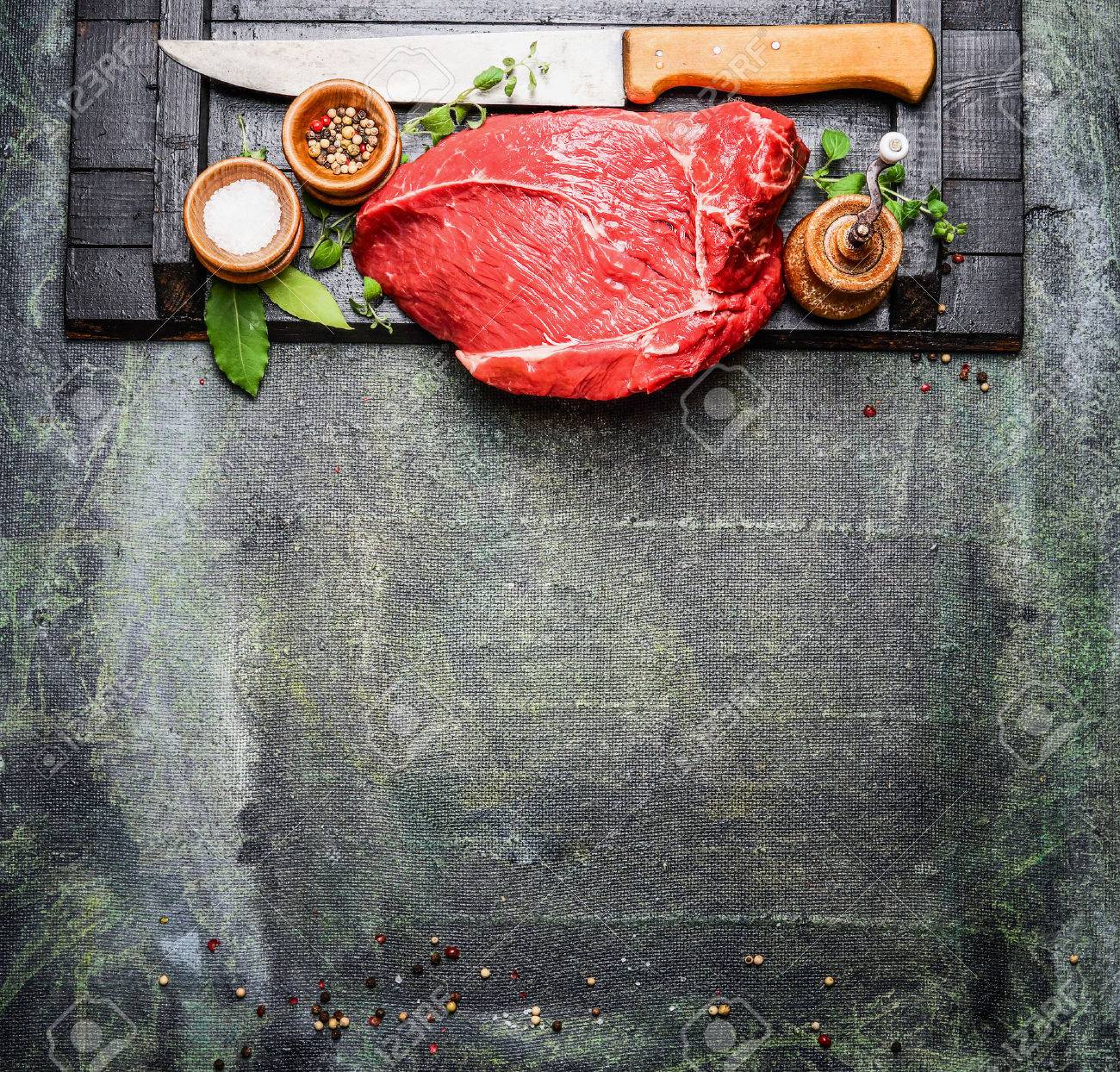 Fresh raw meat with cooking seasoning and butcher knife on rustic background, top view. - 50916258 Fresh raw meat with cooking seasoning and butcher knife on rustic background, top view. - 50916258