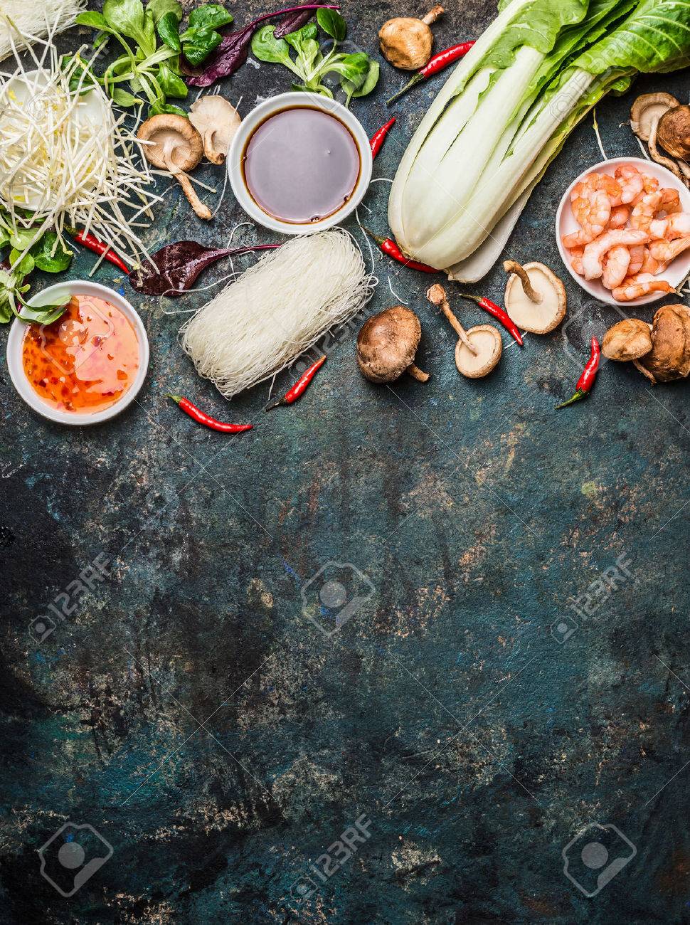 Asian cooking ingredients: rice noodles, pok choy , sauces, shrimps, chili and Shiitake mushrooms on dark background, top view, place for text. Asian food concept: Chinese or Thai cuisine. - 52237376 Asian cooking ingredients: rice noodles, pok choy , sauces, shrimps, chili and Shiitake mushrooms on dark background, top view, place for text. Asian food concept: Chinese or Thai cuisine. - 52237376