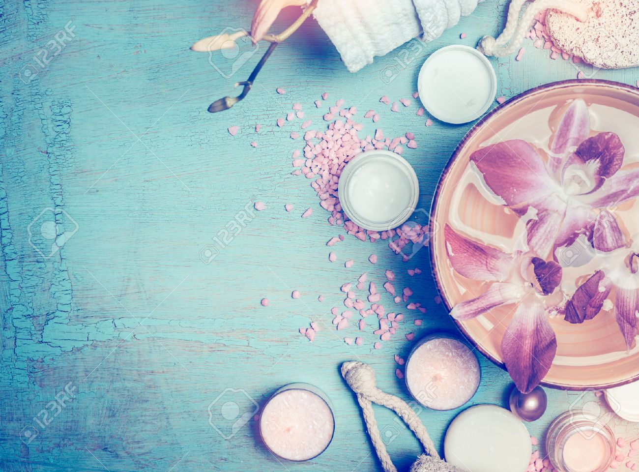 Spa or wellness setting with cosmetic products , water bowl and orchid flowers on blue turquoise shabby chic background, top view, toned - 54220300 Spa or wellness setting with cosmetic products , water bowl and orchid flowers on blue turquoise shabby chic background, top view, toned - 54220300