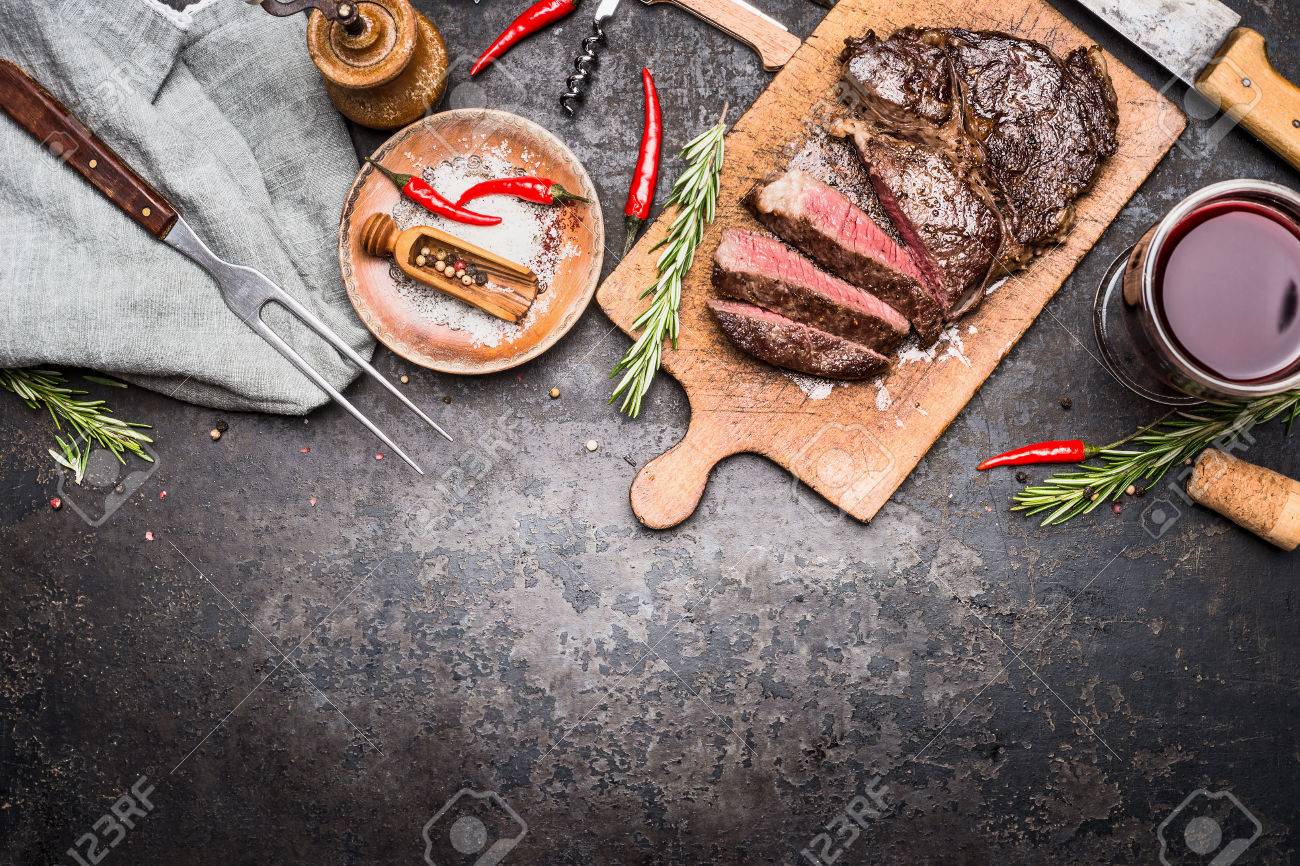 木製まな板の上の暗いビンテージ金属を背景 平面図 国境にフォークをワイン 調味料 肉薄切りグリル ステーキのロースト の写真素材 画像素材 Image