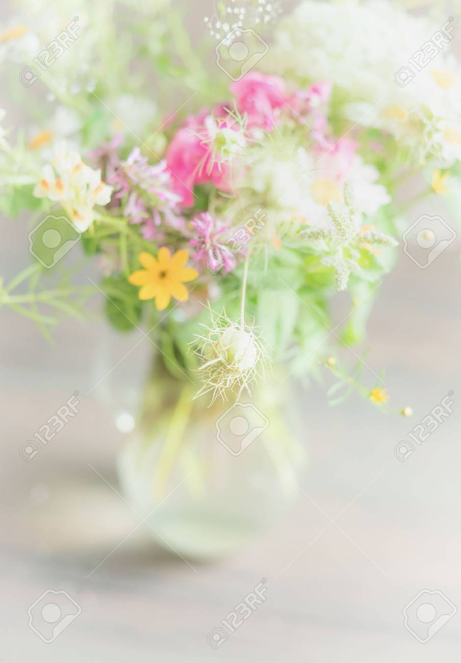Beautiful Wild Flowers Bunch In Glass Vase On Light Background