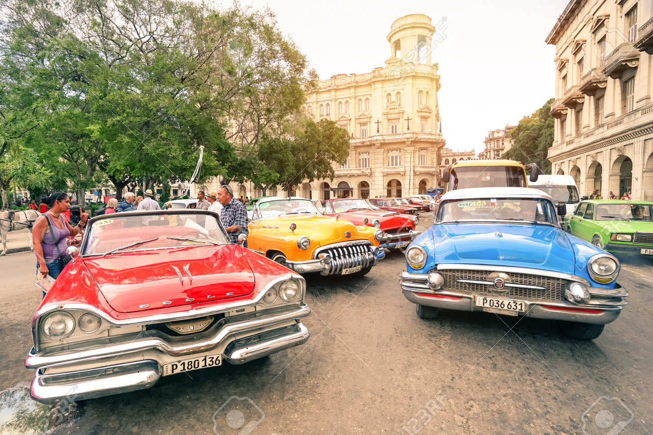 HAVANA, CUBA - NOVEMBER 17, 2015: multicolored vintage american cars in Havana City with National Museum of Fine Arts - Warm afternoon color tones with sunshine halo - 50730988 HAVANA, CUBA - NOVEMBER 17, 2015: multicolored vintage american cars in Havana City with National Museum of Fine Arts - Warm afternoon color tones with sunshine halo - 50730988