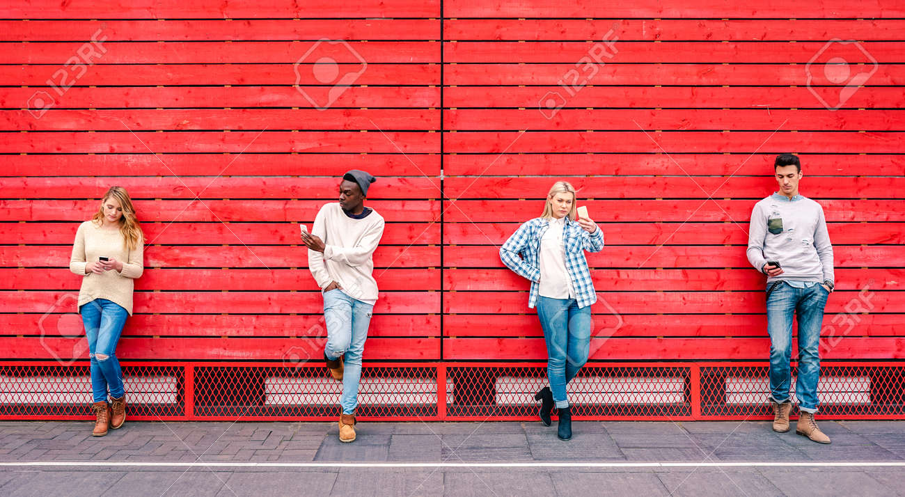 Multicultural friends group using smartphone by red wooden background - Technology and urban lifestyle concept with millenial people sharing content online with modern mobile phones - Vivid filter - 158431852 Multicultural friends group using smartphone by red wooden background - Technology and urban lifestyle concept with millenial people sharing content online with modern mobile phones - Vivid filter - 158431852