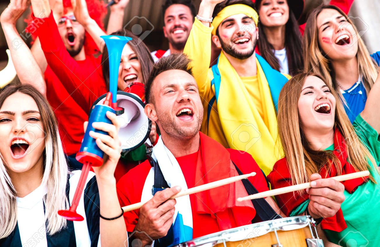 Football supporter fans cheering with drums watching soccer cup match at stadium bleachers - Young people group with multicolored t-shirt having excited fun on sport championship - 170441374 Football supporter fans cheering with drums watching soccer cup match at stadium bleachers - Young people group with multicolored t-shirt having excited fun on sport championship - 170441374