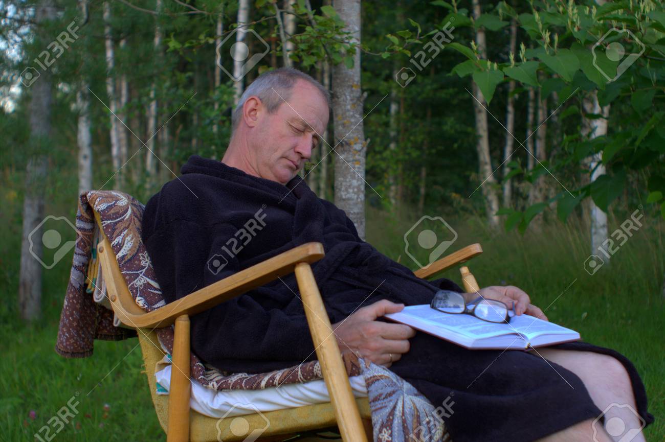 84120479-senior-man-in-night-gown-with-a-book-and-glasses-sleeping-in-rocking-chair-outdoors-.jpg